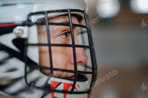 Preview: Close-up of woman floorball goalkeeper in helmet concetrating on game in gym.