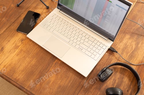 Preview: Laptop with spreadsheet, smartphone, and headphones on wooden desk for remote work, copy space