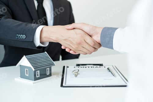 Preview: Businessmen and brokers' real estate agents shake hands after completing negotiations to buy houses