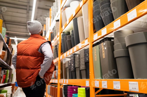 Preview: a man in a building hypermarket looks after a planter for transplanting his plant