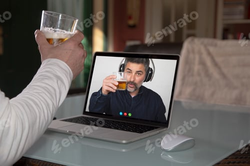 Preview: Person sharing a glass of beer with his friend through a technology platform during quarantine