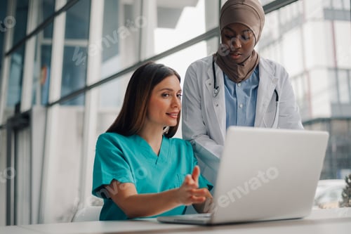 Preview: Two female doctors using laptop are discussing about patient diagnosis in hospital office