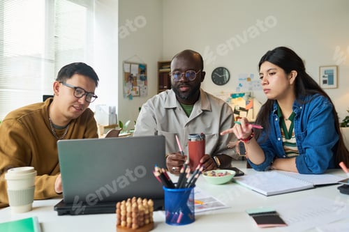 Preview: Multiethnic Adults Collaborating on Project Around Laptop in Office