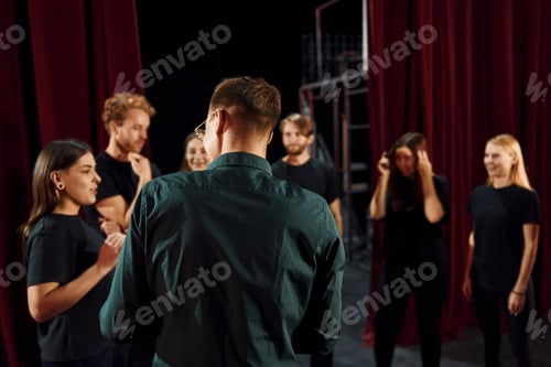 Preview: Working together. Group of actors in dark colored clothes on rehearsal in the theater