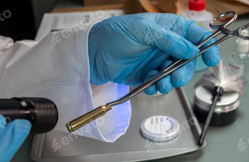 Preview: Forensic police examine bullet casing with UV torch