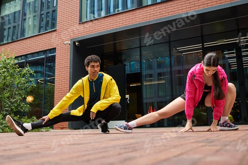 Preview: Dynamic young athletes stretching in a modern urban setting during daytime