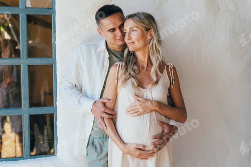 Preview: Loving Couple Embracing Expectant Mother at Home