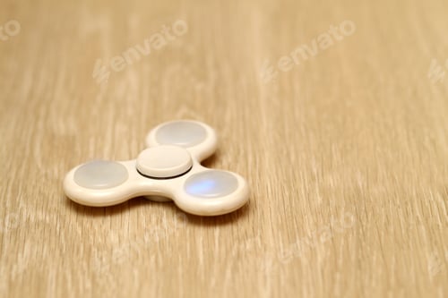 Preview: White fidget spinner toy on a wooden floor