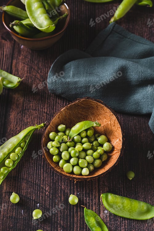 Preview: Bowl with green sugar peas on wooden table vertical view