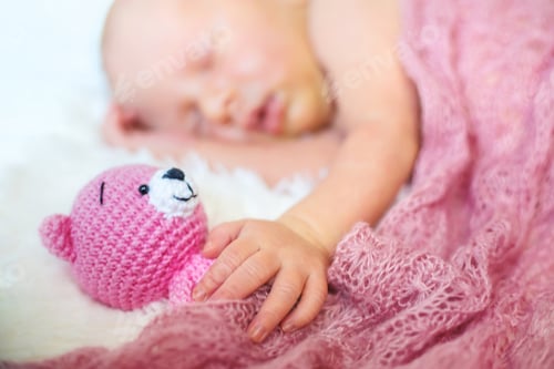 Preview: A newborn baby sleeps with a teddy bear. Selective focus.