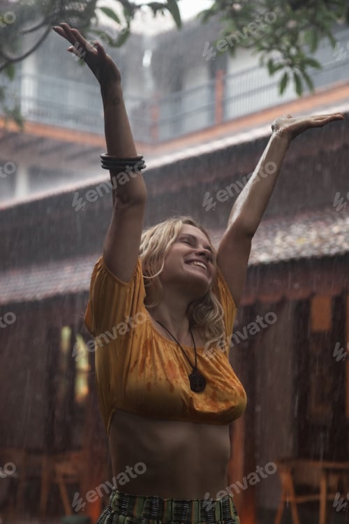 Preview: Young woman in wet clothes is happy in tropical rain
