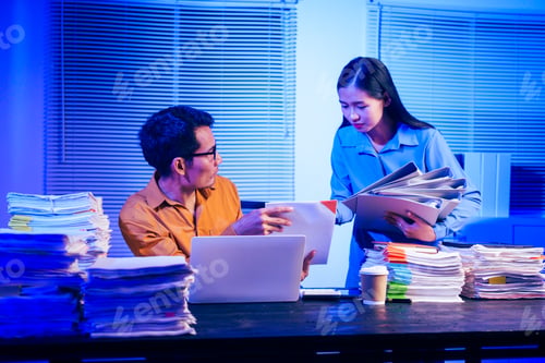 Preview: A businessman and woman are working overtime at their desks office at night.They are busy,stressed