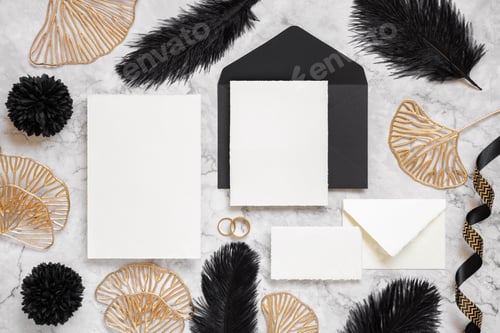 Preview: Cards and envelope on marble table near black feathers and golden leaves. Wedding mockup