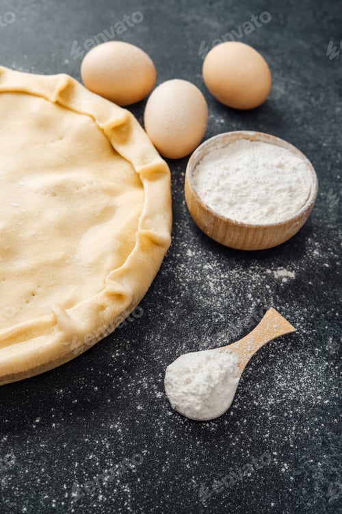 Preview: Preparing pie dough with a rolling pin and different baking ingredients set out.