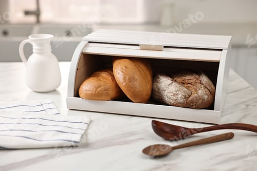 Preview: Wooden bread basket with freshly baked loaves and spoons on white marble table in kitchen