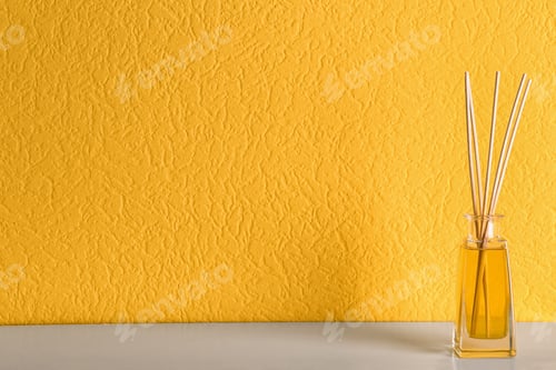 Preview: Reed air freshener on table against orange background, space for text