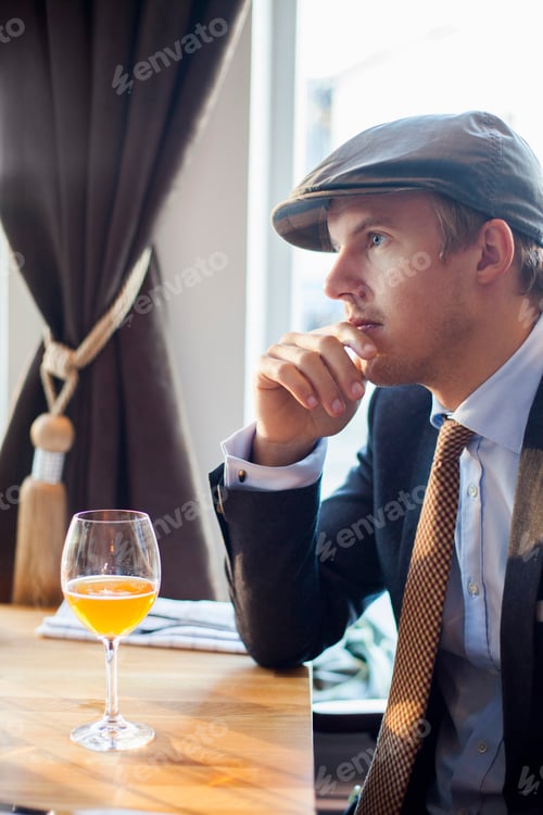 Preview: Thoughtful young gay man looking away sitting at table in restaurant