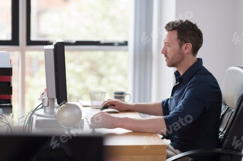 Preview: Man working at computer on office desk