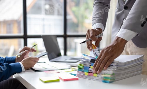 Preview: Businessman and coworkers work on documents on the desk in the office.