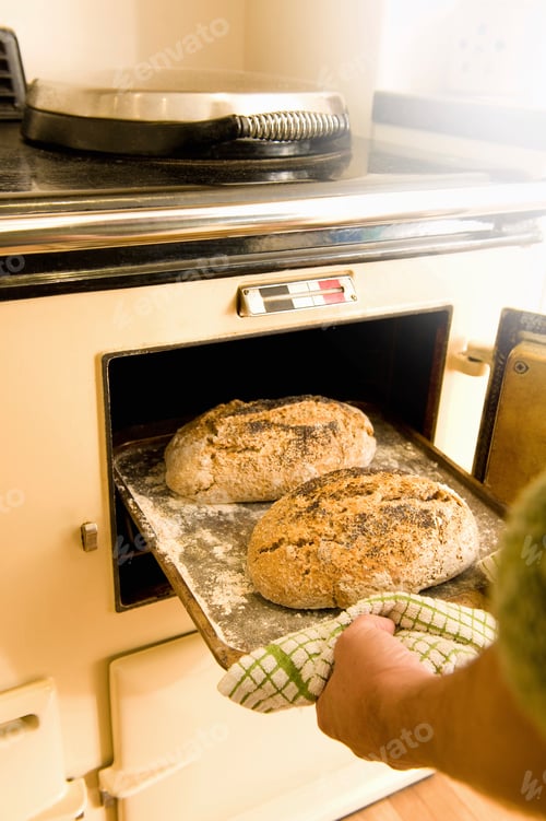Preview: Mature man taking baking tray with fresh bread from oven