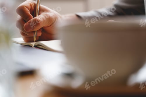 Preview: Young gentleman writing in notebook in cafe