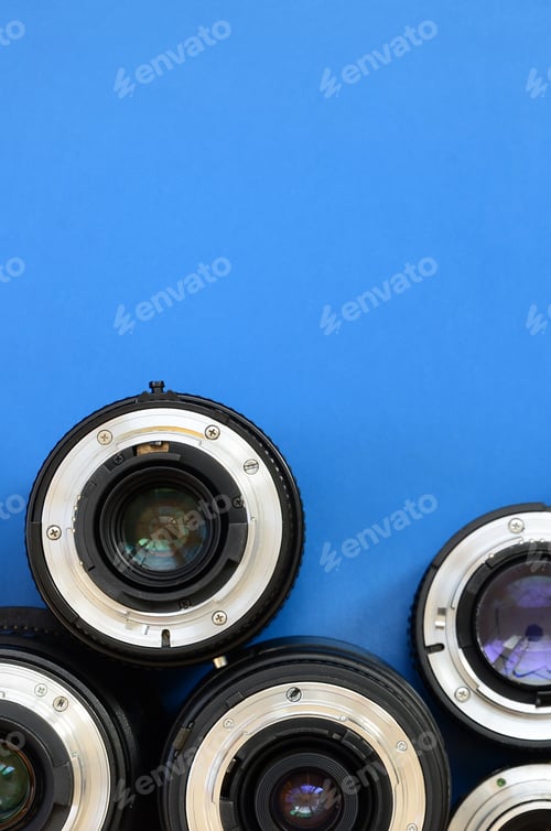Preview: Several photographic lenses lie on a bright blue background. Space for text