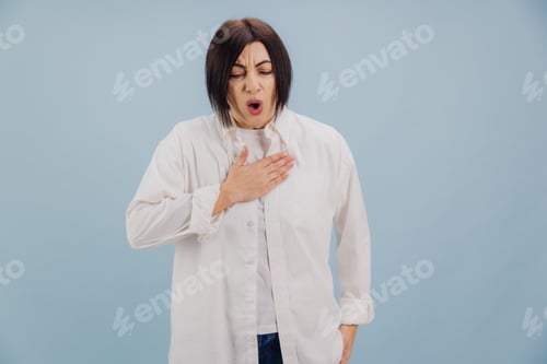 Preview: Sick woman suffering from chest pain, holding hand on heart, breathing heavily on blue background