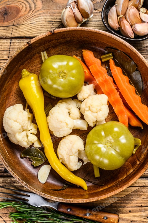 Preview: Salted and pickles vegetables preserve in a wooden plate. wooden background. Top view