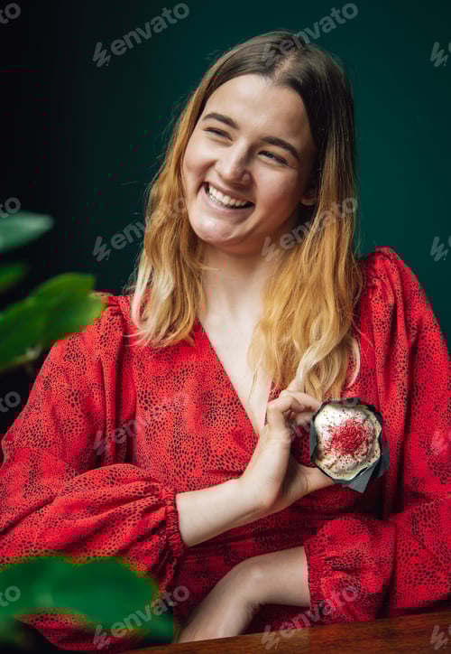 Preview: Funny young woman with a beautiful berry cupcake in a cafe.