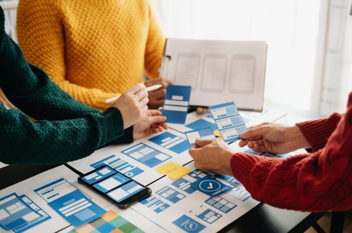 view of UI developer team brainstorming on their project with laptop, smartphone and digital tablet.