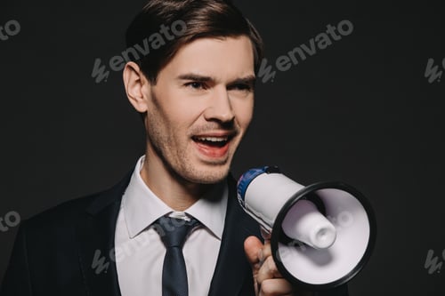 Preview: handsome businessman in suit screaming in megaphone isolated on black