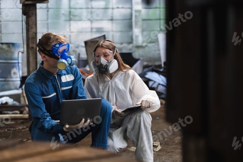 Preview: Team inspector chemical and hazmat wearing protective mask using laptop and write note on clipboard.