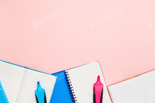 Preview: Back to school concept. Notepads and felt tip pens on pastel pink backdrop. Copy space, top view