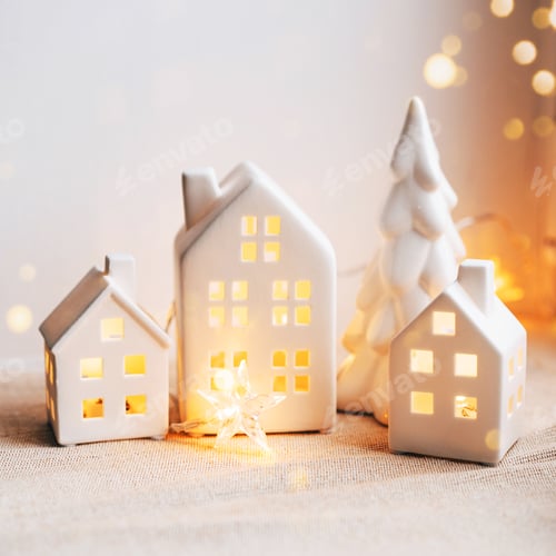 Visualização: Cena de Natal aconchegante com casas de cerâmica e luz de velas perto de uma janela