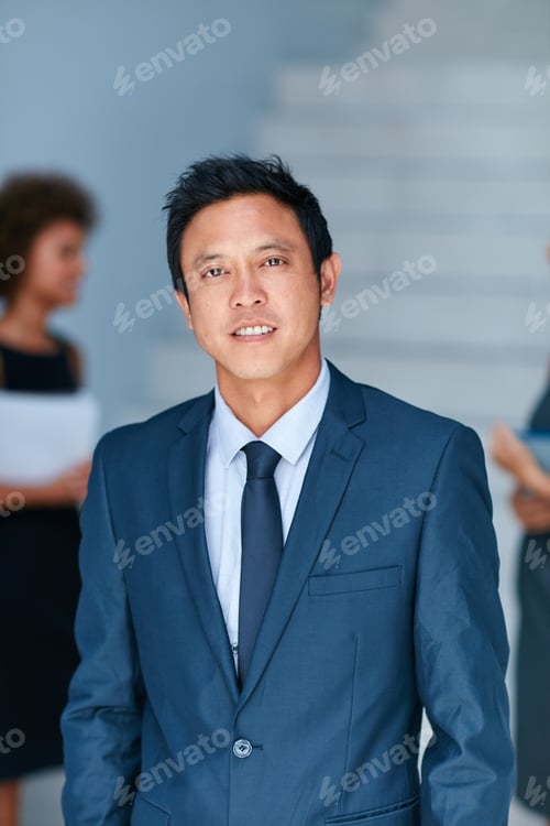Preview: Portrait of a young businessman standing in an office with colleagues in the background