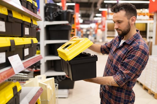 Preview: a male builder in a hardware store chooses a tool storage case