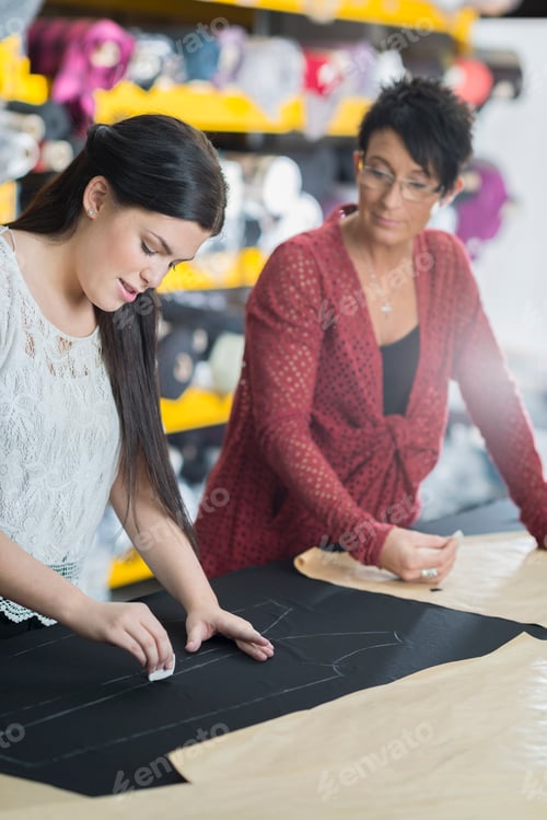 Preview: Two seamstresses chalking outline onto textile on work table