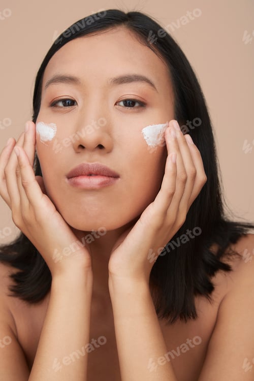 Preview: Portrait of young female Chinese woman applying cream