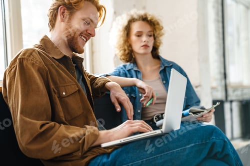 Preview: Young beautiful redhead couple making down notes and working with laptop