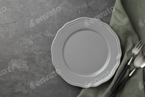 Preview: Stylish setting with cutlery, napkin and plate on grey textured table, top view. Space for text