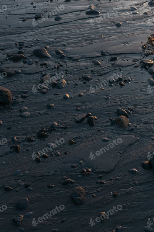 Preview: Rocks creating a beautiful natural pattern on the wet sand on a beach at sunset golden hour