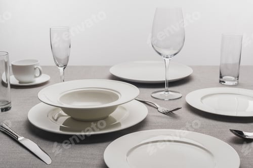 Preview: Dishware and transparent glasses on tablecloth on grey background