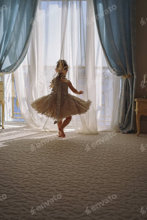 Preview: Cute little girl in fancy dress looking out the window in luxury apartment