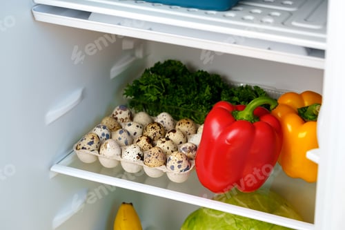 Preview: Open Refrigerator With Fresh Produce, Eggs, And A Blue Container