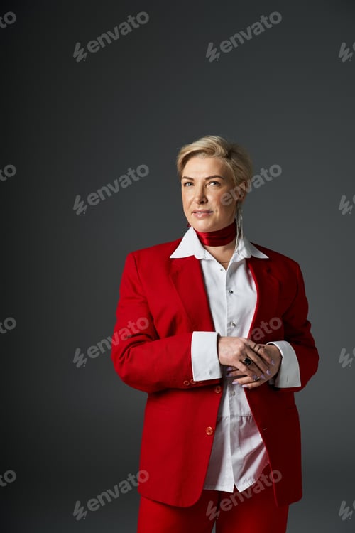 Preview: A confident woman dressed in a striking red suit poses elegantly against a dark background
