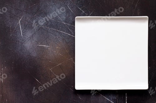 Preview: Food background. White square plate on a dark slate table.