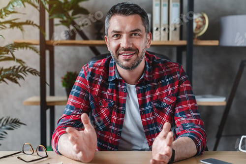 Preview: Middle aged man with gray hair looks at the camera speaks with his partner sitting at table