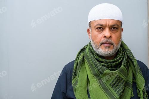 Preview: Portrait of handsome bearded muslim man against plain wall