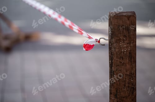 Preview: Signal red-white tape tied to a hook on a wooden pole.