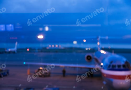 Preview: View through an airport window of airport runways and taxiway at dusk.